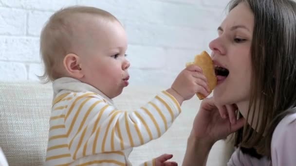 Kind baby voedt mama met grote smakelijke koekje. thuis baby 's eten. Gezond eten, snack of lunchtijd. — Stockvideo