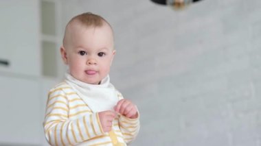 Evdeki meraklı çocuğun portresi. Küçük bebek gülümsüyor ve kameraya bakıyor. Mutlu çocukluk, evde oyunlar