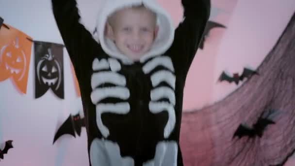 Halloween niños Feliz niño bailando en disfraz de esqueleto de Halloween en casa. Niño está listo para el truco o regalo de vacaciones — Vídeo de stock