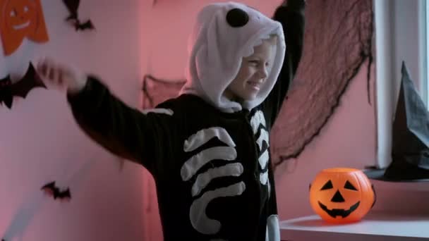 Halloween kinderen Gelukkige dansende jongen in Halloween skelet kostuum thuis. Kind is klaar voor de truc of traktatie vakantie — Stockvideo