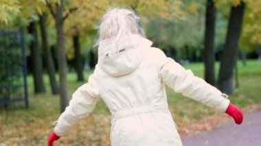 Küçük kız sonbahar turuncu parkında dışarıda eğleniyor. Gülümseyen çocuk