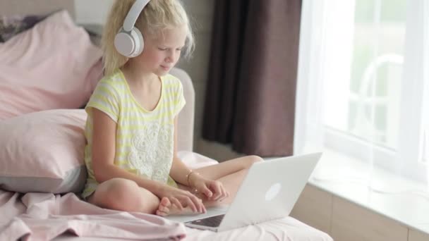 Blondynka ucząca się w domu w łóżku odrabiająca lekcje z laptopem. Kształcenie online na odległość. Wracamy do szkoły. — Wideo stockowe