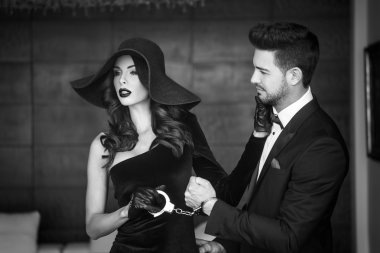 Siyah ve beyaz şapkalı adam tutarak kadın kelepçe