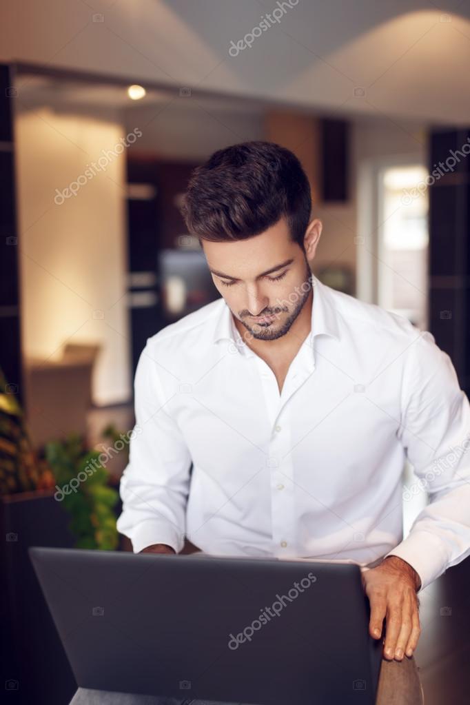 Young rich businessman working on laptop