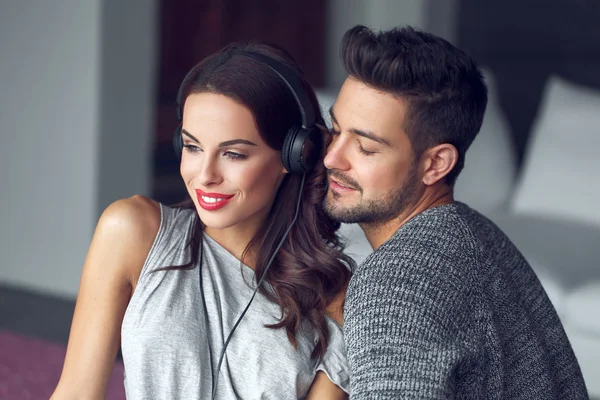 Feliz joven pareja escuchando música en interiores con amor —  Fotos de Stock