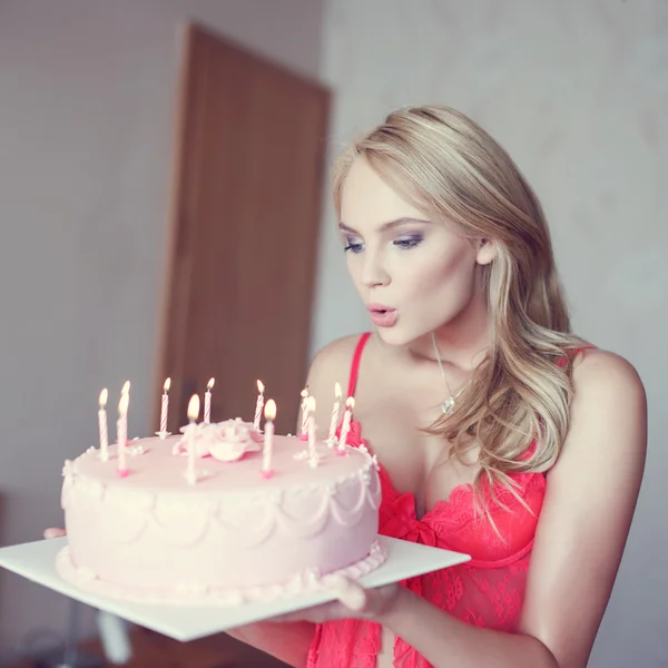 Sexy blonde vrouw blaast de kaarsen op taart in lingerie — Stockfoto