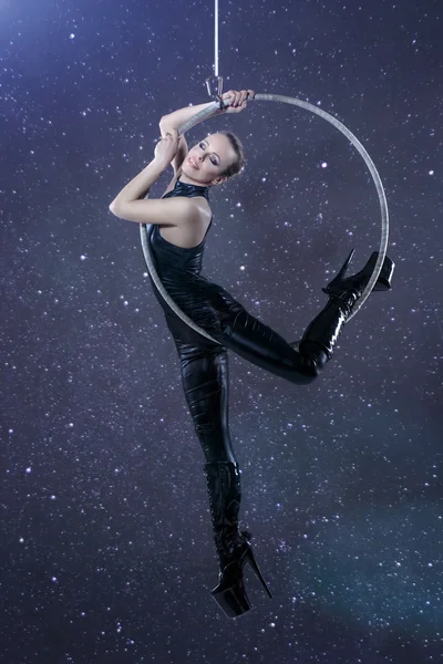 Sexy woman in latex catsuit hanging on aerial hoop at night — Stock Photo, Image