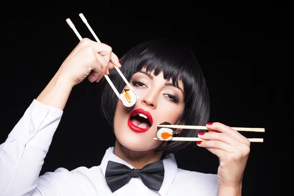 Mujer comiendo sushi por dos palillos — Foto de Stock