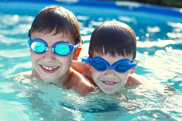 Niños felices con gafas sonríen en la piscina —  Fotos de Stock