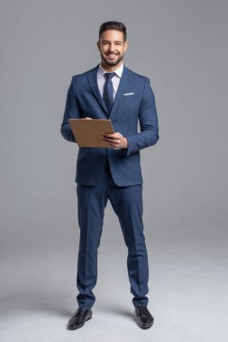 Gri arka planda panosu olan mutlu, kendine güvenen beyaz bir menajer.