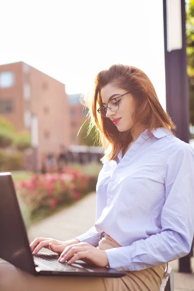 Young freelancer Caucasian programmer woman working on laptop in park