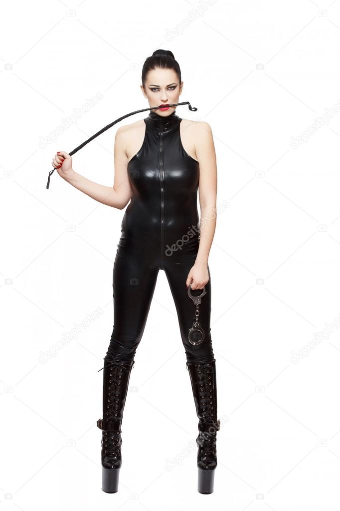 Sexy woman in latex catsuit holding handcuffs and bite whip