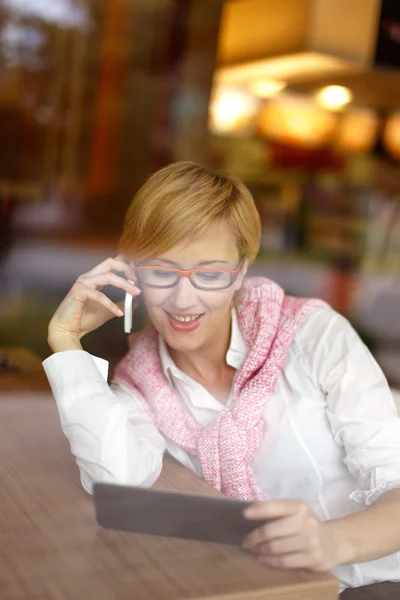 Blonde vrouw oproep in restaurant achter glas — Stockfoto