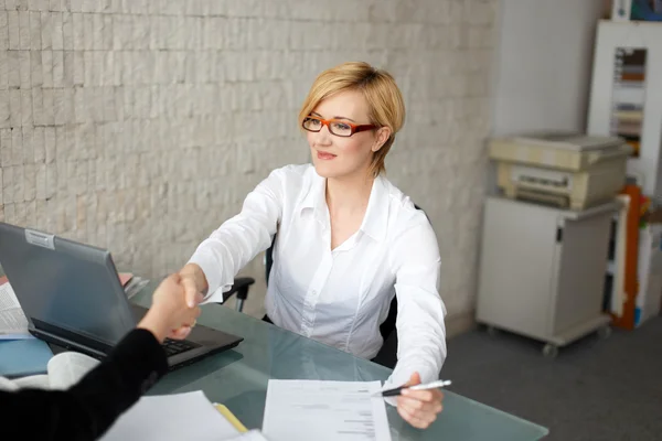 Jonge zakenvrouw handdruk met de client in office — Stockfoto