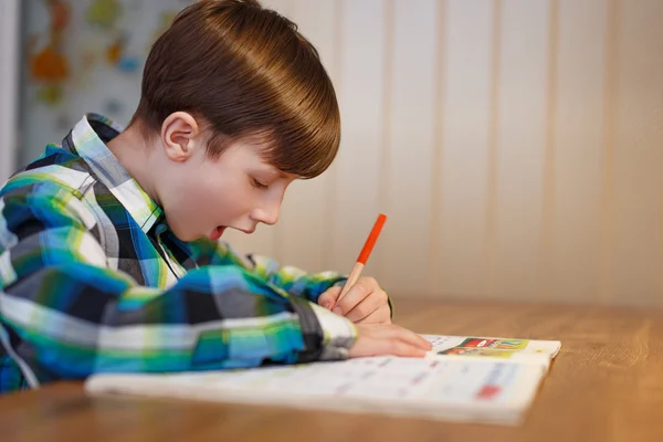 Kleiner Schoolboy macht Fehler in Arbeitsbuch — Stockfoto