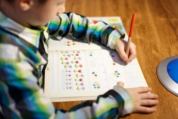 Мальчик пишет домашнее задание по математике — стоковое фото