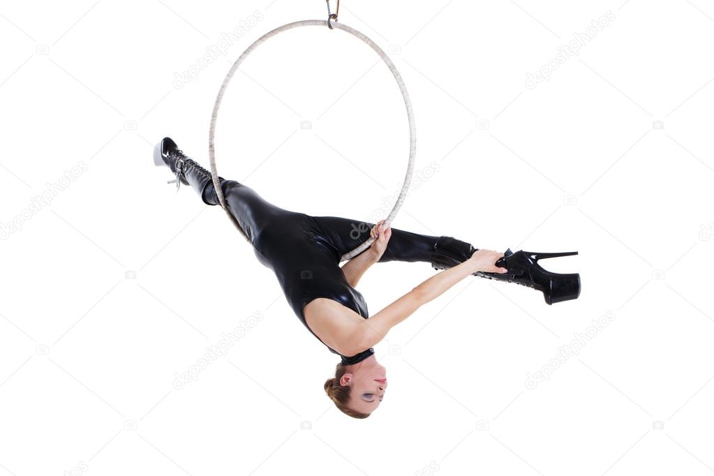 Sexy performer in latex outfit hanging on aerial hoop