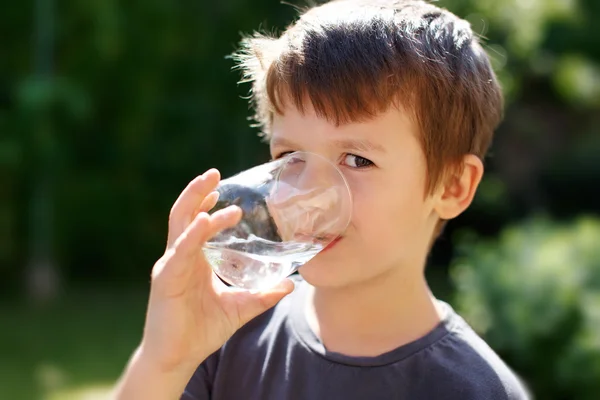 Kleine jongen drinkwater in de natuur — Stockfoto