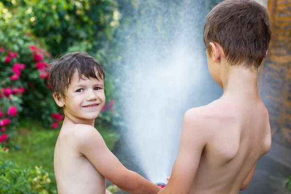 Little kids watering with hose outdoor — Stock Photo, Image