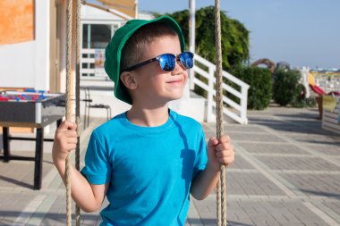 Güneşli yaz gününde açık sallanan küçük çocuk