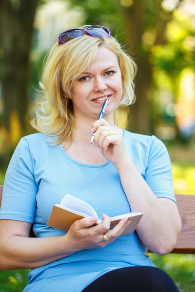 Blonde journalist zitten in park — Stockfoto