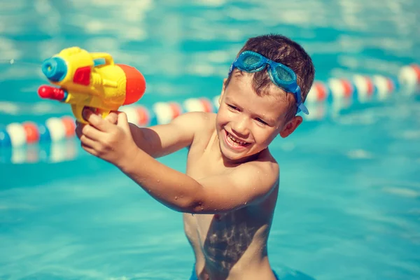 Malý chlapec střílet s pistolí vodu v bazénu vintage — Stock fotografie