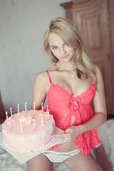Sexy blond kobieta z tort urodzinowy na łóżku — Zdjęcie stockowe