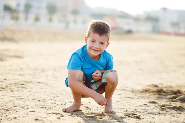 Ragazzino accovacciato in sabbia sulla spiaggia — Foto Stock