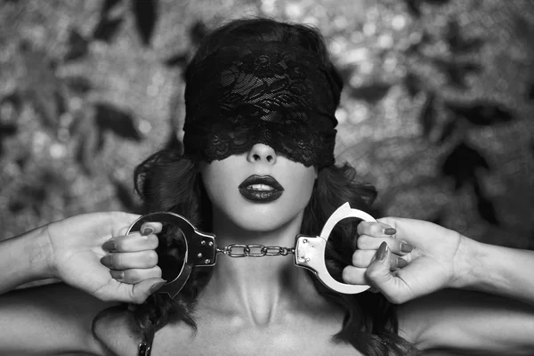 Sexy Frau in Spitze Augenschutz hält Handschellen schwarz und weiß — Stockfoto