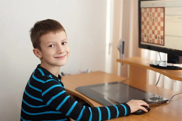 Kleiner Junge lächelt und spielt Online-Schach — Stockfoto