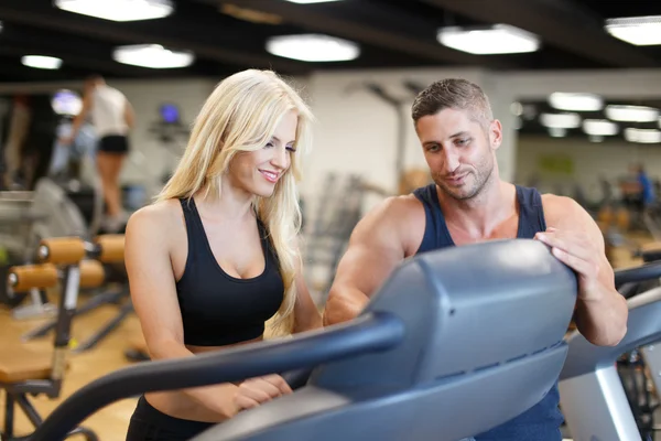 Personal Trainer zeigen Laufband für blonde Frau im Fitnessstudio — Stockfoto