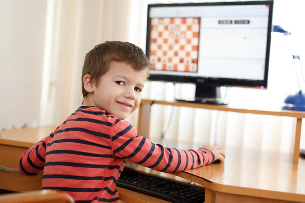 Petit garçon jouant sur PC échecs regardant en arrière — Photo