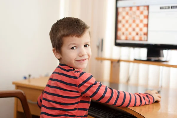 Kleiner cleverer Junge spielt online Schach — Stockfoto