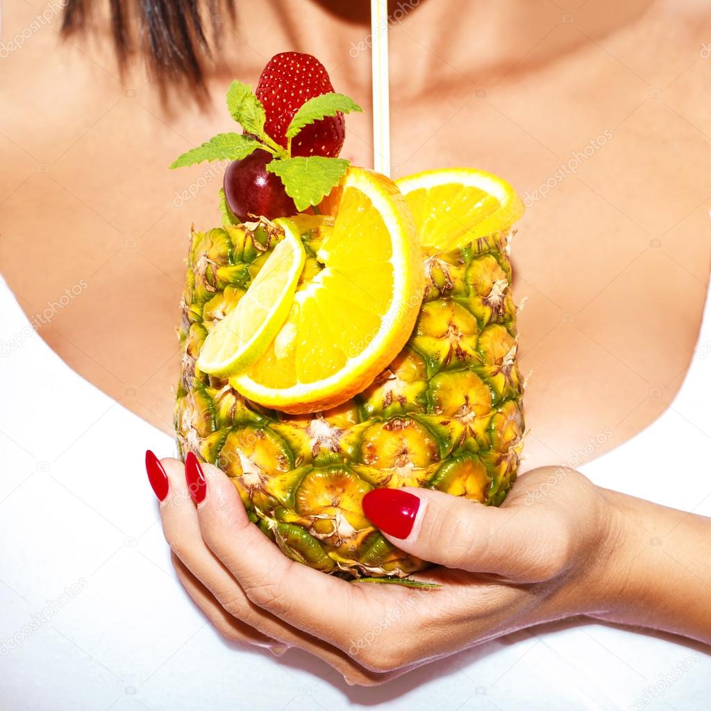 Woman hand holding pineapple cocktail closeup