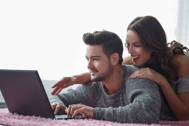 Halıya yüzükoyun yalan dizüstü bilgisayar ile genç Çift