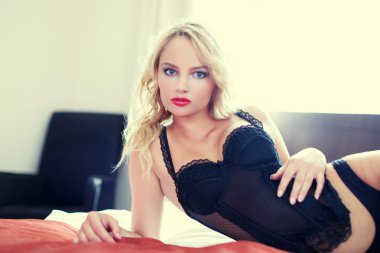 Seksi sarışın kadın yatakta yatarken korse