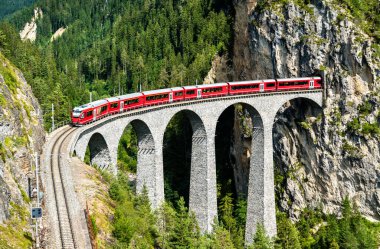 Passenger train crossing the Landwasser Viaduct in Switzerland clipart
