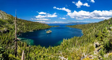 Tahoe Gölü 'ndeki Zümrüt Körfezi ve Fannette Adası panoramik manzarası. Derin mavi su bulutlu bir gökyüzünün altında çam ormanlarıyla çevrilidir.