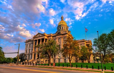 Denver 'daki Colorado State Capitol binası altın saat günbatımıyla aydınlandı. Altın kubbe dramatik bir mavi ve pembe bulutlu gökyüzünün altında parlar.