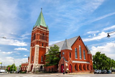 Kansas City Missouri 'deki St. Marys Piskoposluk Kilisesi. Tarihi Gotik Uyanış mimarisi, yeşil bakır kulesi ve mavi gökyüzünün altında kemerli pencereleri olan kırmızı tuğlalı bir cepheye sahiptir.