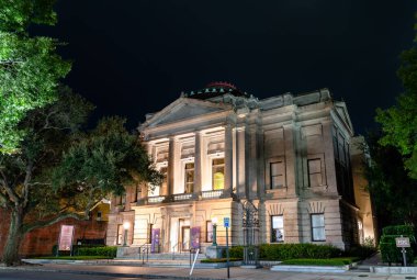 Charleston, Güney Carolina - 28 Ağustos 2025: Gibbes Sanat Müzesi tarihi Beaux-Arts binası Corinthian sütunlarıyla taştan bir cepheye ve Meeting Street 'te geceleri aydınlatılmış basamaklara sahiptir.