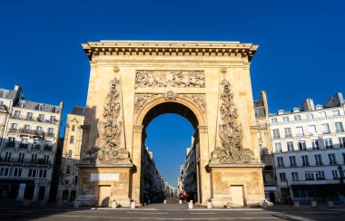 Paris, Fransa 'daki tarihi Porte Saint-Denis kemerinin güneşli manzarası. Karmaşık bas-yardım oymaları ve klasik Paris binaları..