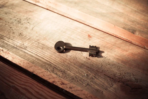 Rusty Old Skeleton Key on Dark Rustic Barnwood With Window Light