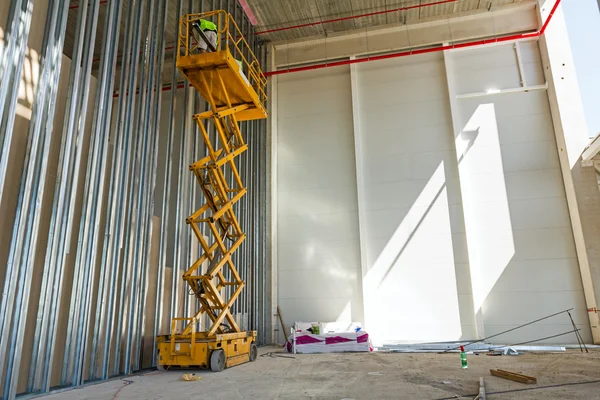 Plataforma elevadora de tijera en una obra de construcción . — Foto de Stock