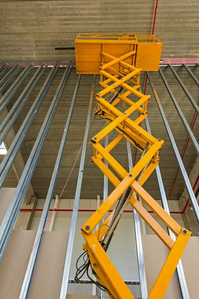 Plataforma elevadora de tijera en una obra de construcción . — Foto de Stock