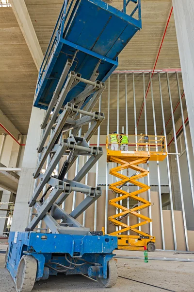 Plataforma elevadora de tijera en una obra de construcción . — Foto de Stock