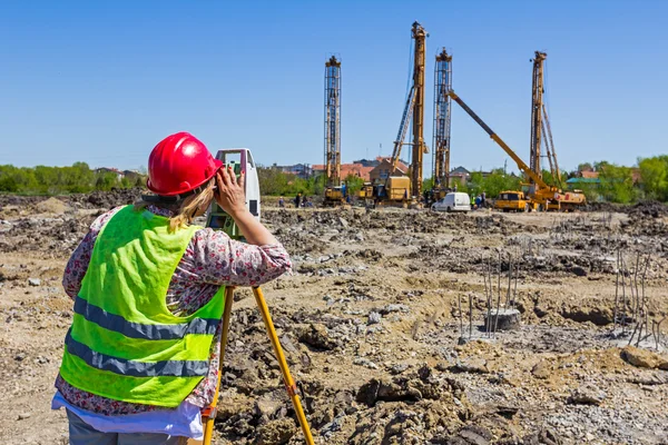 Kadın geodesist bir bina otur toplam istasyon ile çalışıyor