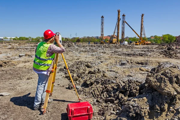 Mujer geodésica está trabajando con la estación total en un edificio sentarse —  Fotos de Stock