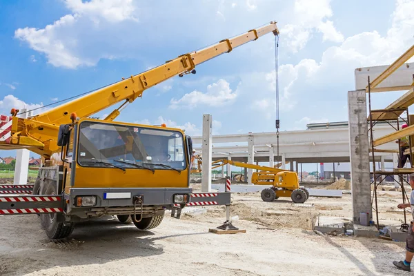 Guindaste móvel está operando e levantando viga de concreto. Paisagem — Fotografia de Stock