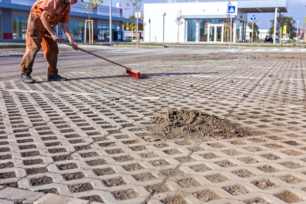 Arbeiter putzt neuen Parkplatz mit rotem Besen — Stockfoto
